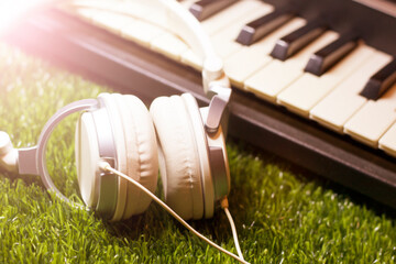 White headphones and synthesizer on the grass