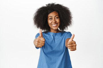 Like. Smiling african american woman showing thumbs up in approval, agree with you, recommending product quality, praising and complimenting, white background - obrazy, fototapety, plakaty
