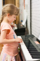 Little girl playing piano home independent. Distance learning.