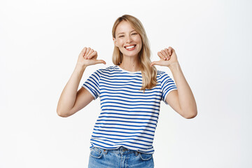 Enthusiastic beautiful woman pointing fingers at herself, self-promoting, talking about personal...