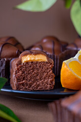 Chocolate candy cake sliced, with orange filling on brown background. Close up chocolate square cake