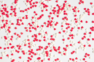 Fototapeta na wymiar Valentine's Day pattern background. Composition with candy hearts from many sugar mini red and white hearts on white background. Flat lay, top view