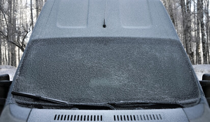Windscreen wipers and a snow covered car or bus.winter season. front view. A frozen car windshield...