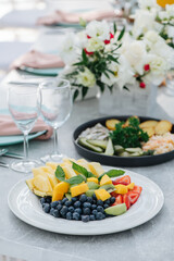 Close up image of a plate with sliced fruit and berries on a banquet table