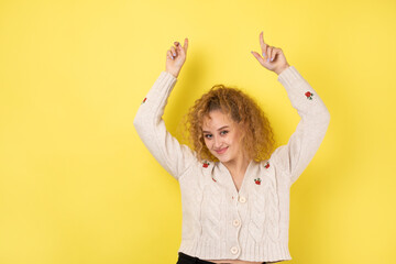 A young girl with curly hair points with a gesture on a studio background.