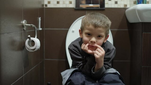a boy sits on the toilet in the restroom