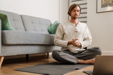 Ginger man using laptop during yoga practice on floor
