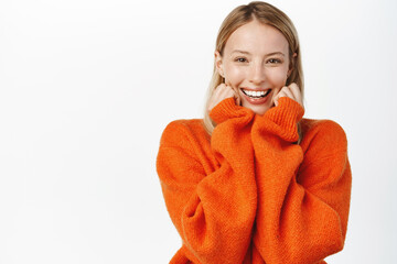Excited cute blond girl looking surprised and amazed, gasping fascinated, reaction to big surprise, amazement and fascination, standing over white background
