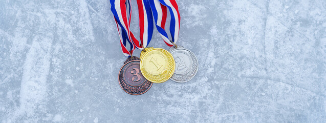 real Gold, silver and bronze medals hanging on red ribbons isolated lying on the ice rink