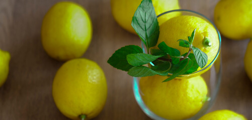 Glass with lemons for home mede lemonade, summer refreshment beverage concept, peppermint, wooden rustic background