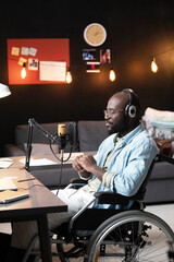 African man with disability sitting on wheelchair and speaking to the microphone during live broadcasting