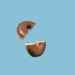 Chocolate glazed donut floating against bright blue background. Summer fun, fast food, treat, snack. 