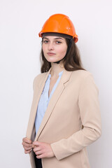 A girl architect in a suit and an orange construction helmet stands on a white background.