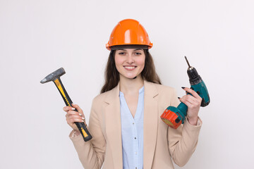 Girl engineer in an orange construction helmet with a screwdriver and a hammer on a white background.