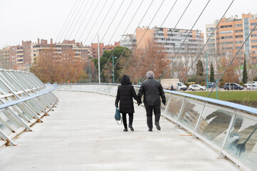 couple walking along the volunteer footbridge over the ebro river in zaragoza spain.