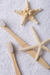 A set of eco-friendly bamboo wooden toothbrushes with starfish on a white towel.