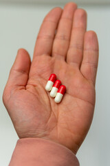 A vertical shot of a man's hand with a handful of pills on top ready to be ingested. Human hand holding alternative
medicine pills against coronavirus.