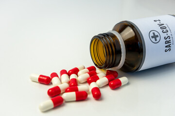 Bottle of pills with some of them out. A close up shot of an open pillbox against covid-19 on the table.