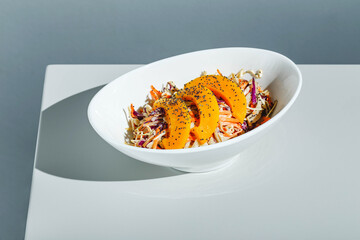 Cole slow salad with mango and poppy seeds on light background. Hard light, deep shadow
