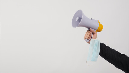 Megaphone and face mask in Male Hand and he wear black shirt on white background. Studio shooting.