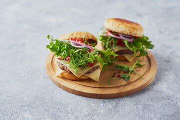 Two burgers with veal cutlet and herbs on wooden cutting board