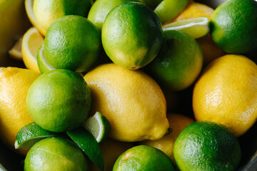 Green limes and yellow lemons in a texture. Famous sour fruits.