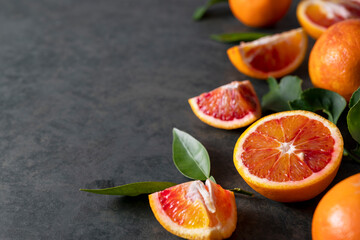 Bloody oranges slices with fresh leaves. Abstract citrus fruit background with copy space.