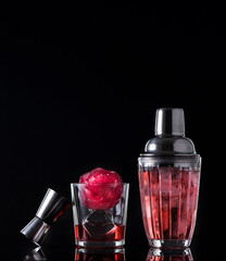 Red drink with ice and bar shaker, black background