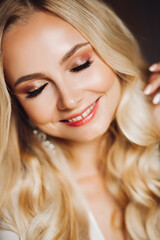Sedactive and attractive blondie wearing makeup and smiling at camera.