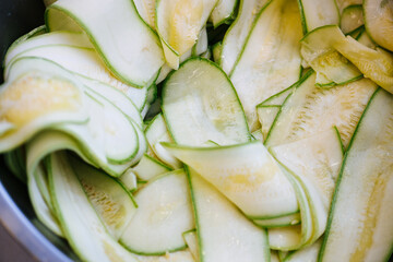Thin cucumber slices in a one wet pile in a metal bowl. Close up, food texture.