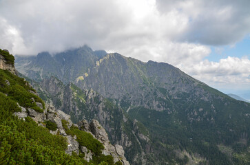 Sharp rocky high ridges of mountain ranges covered with trees and vegetation under a cloudy sky. High Tatras, Slovakia