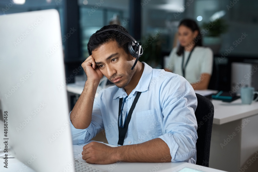 Poster rude callers really do my head in. shot of a young man using a headset and looking depressed in a mo