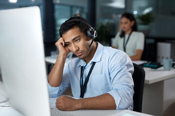 Rude callers really do my head in. Shot of a young man using a headset and looking depressed in a modern office.