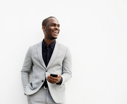 African American businessman laughing holding cellphone by isolated white background