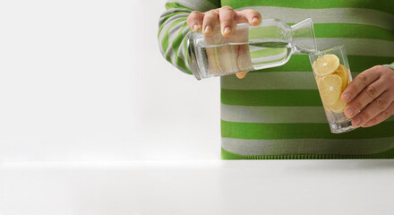 man pouring water from bottle to transparent glass  on background  kitchen interior. no face.