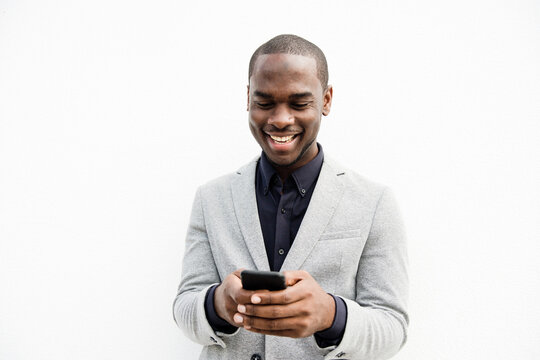 smiling black businessman using cellphone by isolated white background