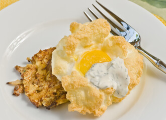 top view, close up of a nested pouched egg on a bed of roasted crab meat on a white plate with an artisan fork