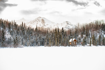 Small cabin on the side of a frozen lake in Alaska