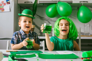 Funny boy and girl at the celebration of Saint Patrick's Day drink green lemonade.
