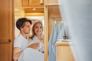 Young just married couple traveling in camper,house on wheels,trailer,motor home.Love romantic road travel,freedom life. Small bed,bedroom in van.Wanderlust vacation,weekend. Girl,guy,happy adventure