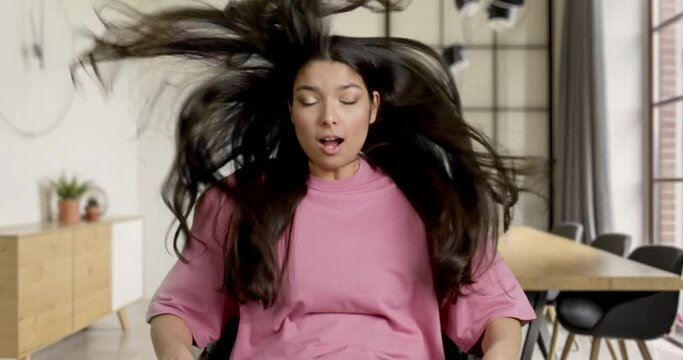 VERTIGO EFFECT Young female sits in front of TV screen in an armchair with a remote in her living room, gets blown away