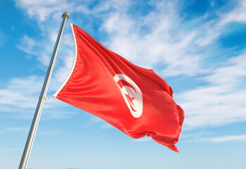 3d rendering Tunisia flag waving in the wind on flagpole. Perspective wiev Tunisia flag waving a blue cloudy sky