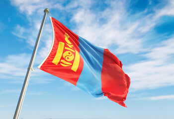 Mongolia flag waving in the wind on flagpole. Mongolia flag waving a blue cloudy sky