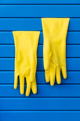 Yellow dishwashing gloves hung on a blue shutter - 485876892