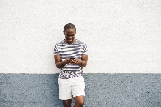 smiling african american man in shorts and t-shirt looking at mobile phone