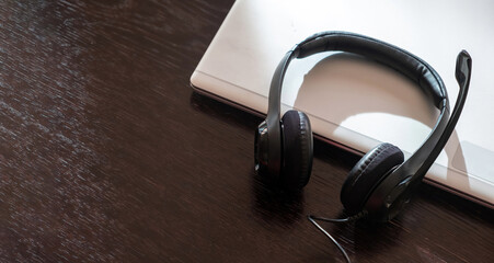 Headset on a laptop, wooden table. Call center, home office, customer support, help desk