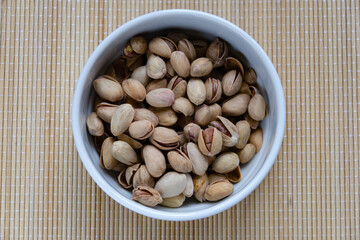 Roasted salted pistachios in a basket, plate on a white background