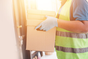 Corona Virus concept. Delivery cargo worker holding parcel box with protective mask and rubber medical gloves holding parcel box of online delivery goods at home.
