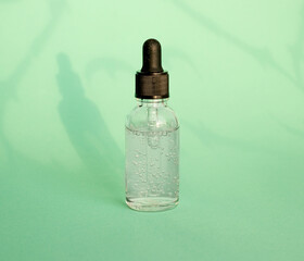 Cosmetic bottle with serum, hyaluronic acid for skin care on the background of shadows. Beauty and body care product concept