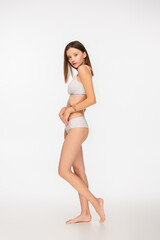young and slim woman in underwear looking at camera on white background